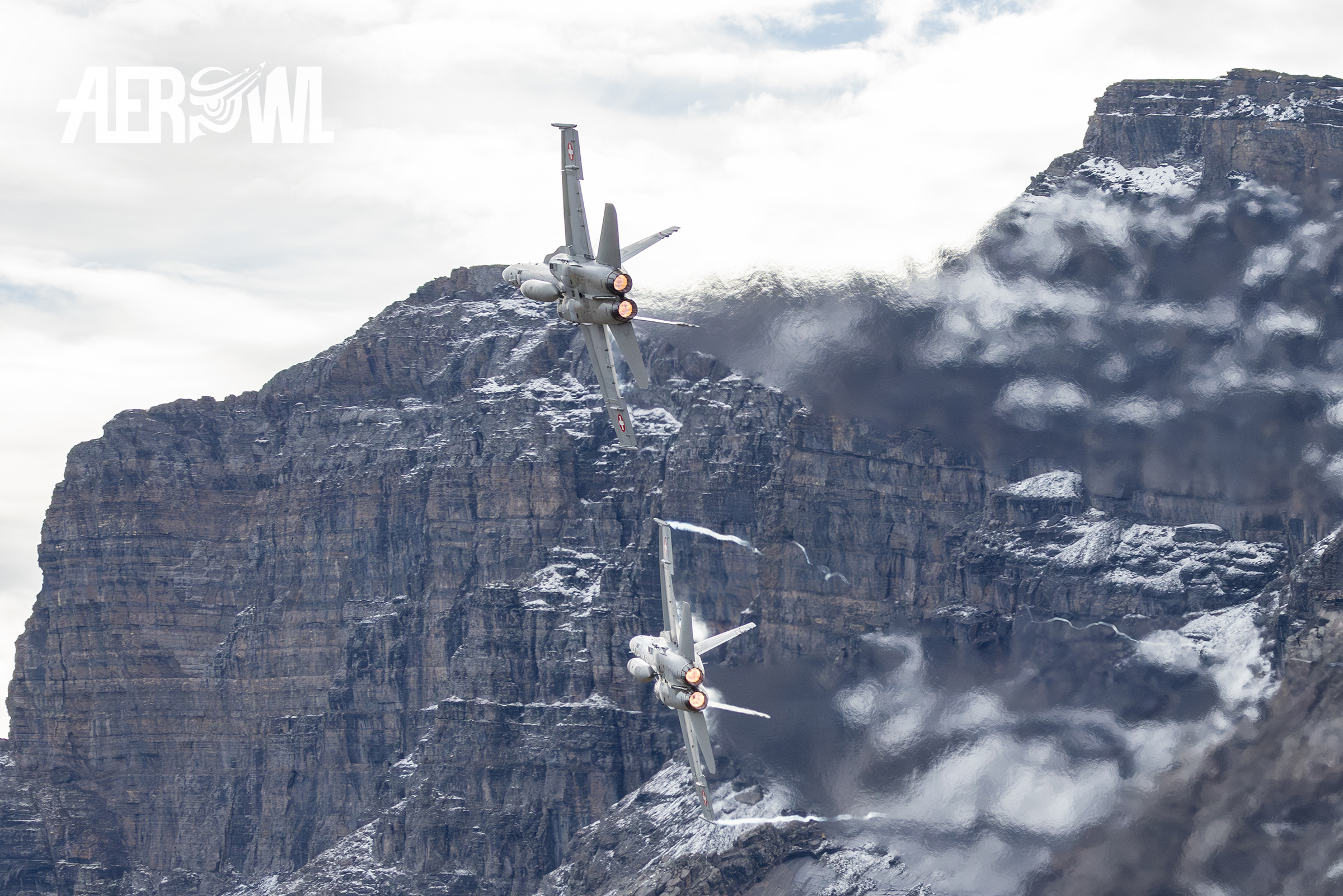 Two Boeing F/A-18C Hornet of the Swiss Air Force with afterburner in a hard turn at the Axalp Fliegerschiessen 2023 in the Swiss Alps.